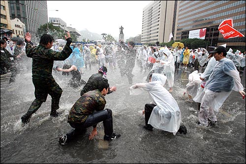 한미 쇠고기 재협상을 촉구하는 48시간 릴레이 농성이 벌어지는 가운데 22일 새벽 서울 세종로네거리에서 밤새워 시위를 벌였던 시민과 예비군들이 폭우로 생긴 물웅덩이에서 물장난을 치고 있다.