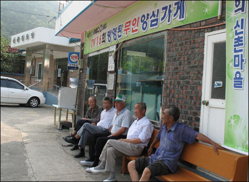 농사일을 끝낸 신촌마을 사람들이 무인 양심가게 앞에 앉아 휴일 오후시간을 즐기고 있다.