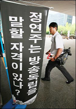 KBS 방송 카메라 기자가 2008년 6월 23일 오후 서울 여의도 KBS 본관 앞에 정연주 사장 퇴진을 요구하는 만장 옆을 지나고 있다.