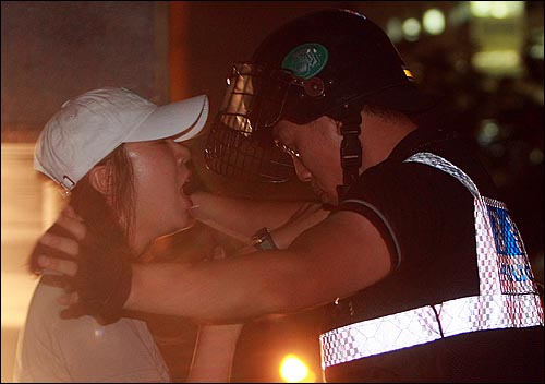 25일 밤 서울 세종로 사거리에서 장관고시 철회와 전면 재협상을 요구하며 시위를 벌이던 한 여성참가자가 광화문 금호아시아빌딩 뒷편 골몰길로 진입을 시도하다가 경찰에게 저지되고 있다.