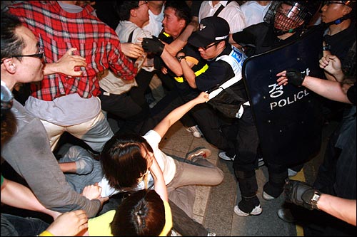 미국산 쇠고기 장관고시에 반대하며 25일 밤 서울 종로구 내수동 서울지방경찰청 부근에서 시위를 벌이던 시민들이 강제연행된 시민들을 태우고 가는 경찰버스를 막고 시위를 벌이다 밀고들어오는 경찰들과 뒤엉켜 넘어지고 있다.
