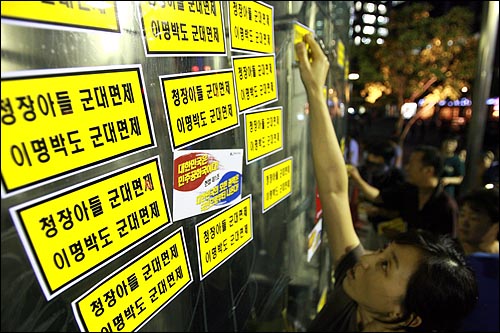  미국산쇠고기 수입 위생조건 고시 강행 철회를 촉구하는 시민들이 26일 저녁 서울시청앞에서 50차 촛불문화제를 개최한 뒤 동아일보사 건물에 각종 스티커를 붙이고 있다.