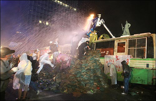 미국산 쇠고기 장관고시 철회와 전면 재협상을 요구하는 시민, 학생들이 26일 밤 서울 세종로 사거리에서 시위를 벌이는 가운데 경찰이 시위대를 향해 살수차로 물을 뿌리고 있다.