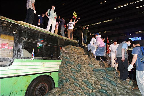 미국산 쇠고기 장관고시 철회와 전면 재협상을 요구하는 시민, 학생들이 26일 밤 서울 세종로 사거리를 가로막고 있는 경찰버스옆에 모래주머니로 '국민토성'을 쌓아 버스위로 올라가고 있다.