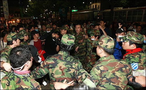  미국산쇠고기 수입위생조건 장관고시 무효와 전면 재협상을 촉구하는 시위가 28일 새벽 서울시의회앞에서 열리는 가운데 대열에서 이탈된 한 경찰이 예비군들에게 둘러싸여 안전한 곳으로 이동하고 있다.