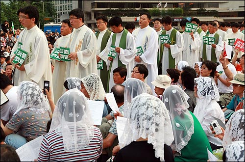 30일 오후 시청 앞 서울광장에서 열린 비상시국 미사에서 천주교 정의구현 전국사제단의 신부들이 고시철회 손피켓을 들고 나오고 있다.