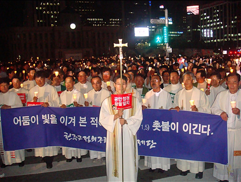 촛불미사를 마치고 십자가를 들고 거리행진을 하고 있는 천주교정의구현사제단의 모습