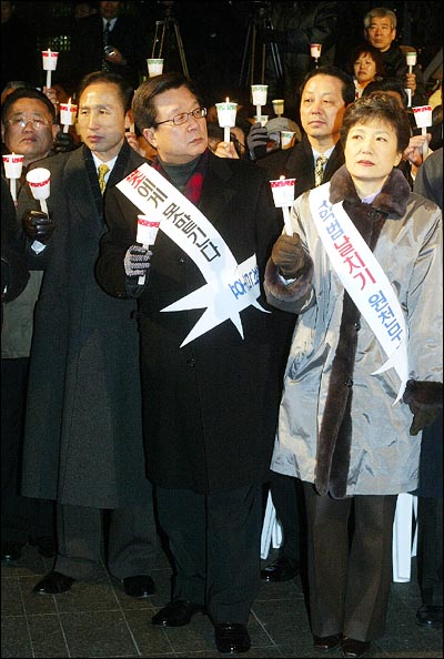 당시 이명박 서울시장, 강재섭 원내대표, 박근혜 한나라당 대표가 촛불을 들고 나란히 서 있다.