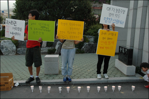 아수나로 회원들이 용마고 정문 앞에 촛불을 켜놓고 피켓을 들고 서 있다.