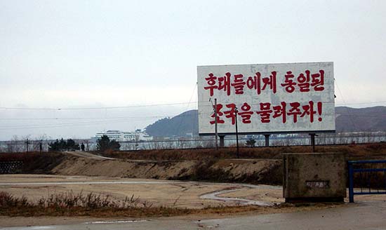 2003년 11월 당시 북측 고성군 시내로 가는 도로가에서 본 현재의 금강산 해수욕장 방향 모습. 대형 선전간판 왼쪽 편에 경계를 서는 북측 인민군의 모습이 보인다. 