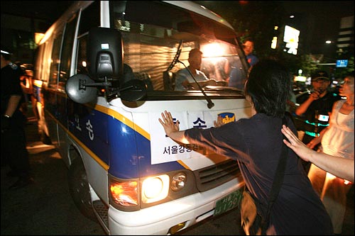 18일 새벽 서울 종로3가역 부근에서 국민주권실천 촛불대행진에 참석한 시민들을 지원하기 위해 참여한 '촛불다방' 승합차 운전자를 경찰이 강제연행하자 시민들이 호송차를 가로막고 항의하고 있다.