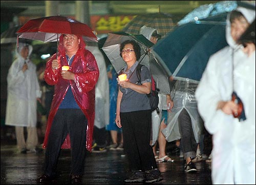 20일 새벽 서울 종로1가 한국수출보험공사 앞에서 장대비가 쏟아지고 있는 가운데 누리꾼과 시민들이 미국산 쇠고기 전면 재협상과 정부의 정책에 항의하며 촛불을 들고 시위를 하고 있다.