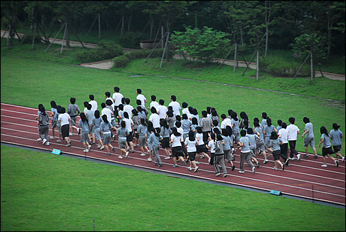 푸른교실에 참가한 100여 명의 학생들이 "복장단정"이라는 구호를 외치며 운동장을 달리고 있다.
