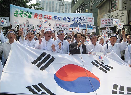광복회 회원들이 커다란 태극기를 들고 일본대사관으로 행진하고 있다.
