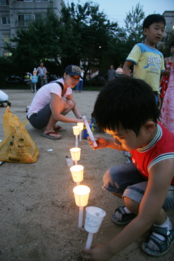 부평5동 촛불문화제에 참가한 한 어린이가 촛불을 바닥에 일렬로 세워놓고 있다.