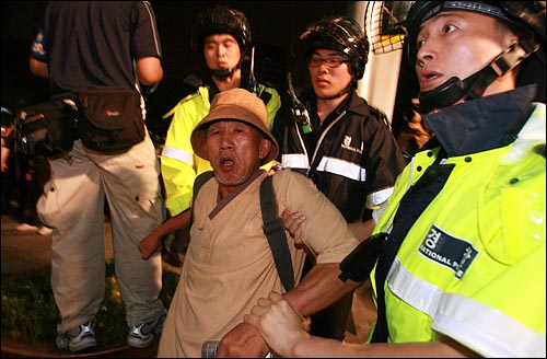 26일 밤 서울 종로 보신각 네거리에서 '미친소 미친교육 반대! 이명박 심판! 제80차 집중촛불문화제'에 참석했던 누리꾼과 시민들이 가두시위를 벌이는 가운데, 경찰들이 한 시민을 강제연행하고 있다. 