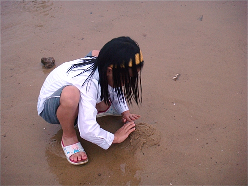 아이가 만리포 해수욕장에서 모래성을 쌓고 있다.