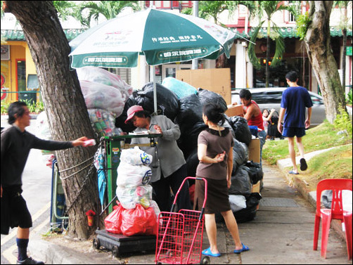 싱가포르에선 돈을 받고 종이를 판다. 수집인이 값을 계산하기 위해 무게를 달고 있다.