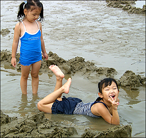 파헤쳐진 모래갯벌에 물이 고이자 그곳에서 놀고 있는 아이들 