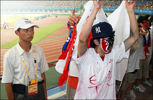  2008 베이징올림픽축구 D조 예선 한국과 카메룬의 경기가 펼쳐진 7일 친황다오 스포츠센터스타디움에서 중국 안보요원이 다소 경직된 표정으로 한국 응원단의 현란한 응원전을 지켜보고 있다.