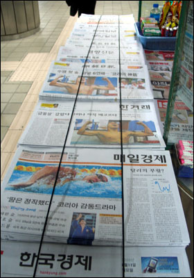 가판대 앞에 신문들이 가지런히 정렬되어 있다. 온통 1면은 박태환 선수의 금메달 소식이다.