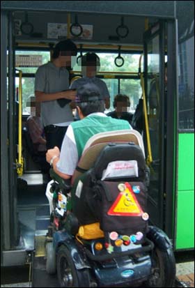저상버스 차량으로 휠체어를 탄 지체장애인이 들어가고 있다. 