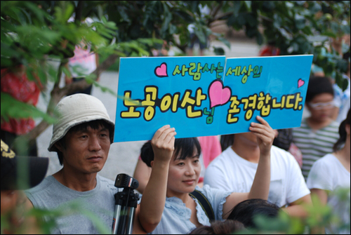 봉하마을을 찾은 한 방문객이 노무현 전 대통령을 존경한다는 내용의 피켓을 들고 서 있다.