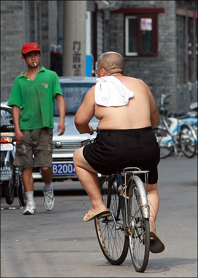 베이징의 '골목'을 뜻하는 후통은 베이징 전통 가옥들이 다닥다닥 붙어있는 서민들의 고향이다. 뙤약볕이 내리쬐는 거리에서 한 주민이 더위를 못 참겠다는 듯 웃통을 벗은 채 자전거를 타고 있다.