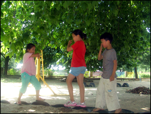  혜진이 삼남매가 학교 운동장에서 가위바위보 놀이를 하며 즐거운 시간을 보내고 있다.