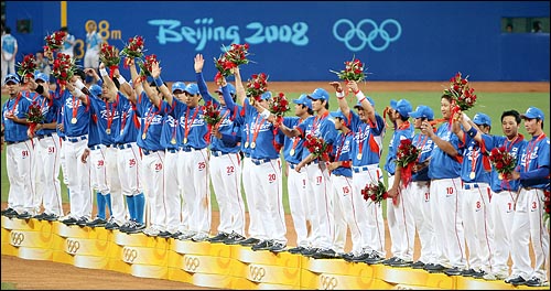  한국야구대표팀 선수들이 23일 저녁 베이징 우커송야구장에서 열린 올림픽야구 결승전 쿠바와의 경기에서 3대2로 승리한 뒤 시상식에서 취재진을 향해 손을 들어보이고 있다.