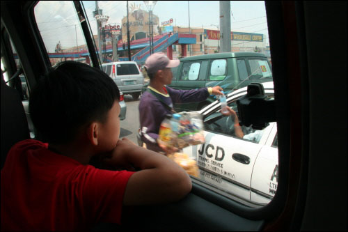 현석이가 마닐라 국제공항으로 가는 길에 차창 밖으로 거리에서 물건을 파는 사람들을 물끄러미 쳐다보고 있다.