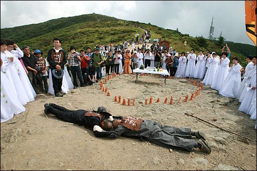 오체투지 순례에 나서는 수경스님과 문규현 신부가 수십명의 신도와 시민들이 지켜보는 가운데 오체투지를 하며 손을 맞잡고 있다.