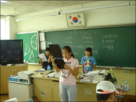 학급 서기가 회의록을 낭독하는 모습  기타토의가 끝나고, 학급 서기(구나영)가 회의록을 낭독하고 있다. 