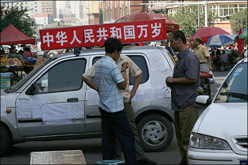 중국 정부기관의 선전차량 앞에서 휴식을 취하는 위구르 남성들. 중국정부의 노력에도 불구하고 독립운동 세력에 협조하는 위구르인의 발길은 더욱 늘고 있다.