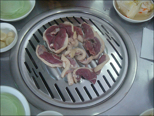 치이칙 맛있는 소리를 내며 하얀 연기 속에 노르스럼하게 익어가는 오리로스를 바라보자 소주 생각이 절로 난다