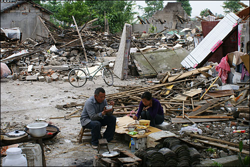 폐허가 된 집 앞에서 간신히 건진 식기로 식사를 하는 쓰촨성의 한 피해지 이재민 부부.