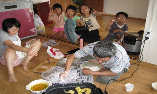  제수씨와 함께 명태전을 굽고 있습니다. 맨 오른쪽 막내, 딸, 그리고 조카들이 아빠와 작은 엄마가 명태전을 굽고, 엄마가 사진찍는 모습을 보면서 즐거워하고 있습니다.