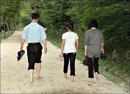 일가족이 해가 질무렵 오붓하게 맨발 산책을 하고 있다. 화목해 보인다.
