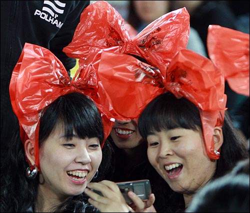 롯데 팬들이 28일 부산 사직야구장에서 열린 기아와의 시즌 마지막 홈 경기에서 붉은 비닐 봉지를 쓰고 찍은 사진을 보며 웃고 있다.