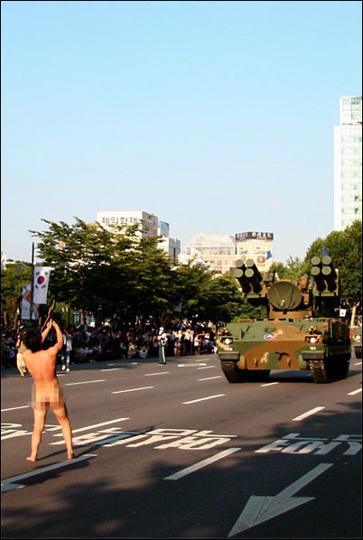 10월 1일 국군의 날, '비무장'한 몸으로 '완전비무장' 탱크 앞에서, 빵으로 만든 총을 먹으며 군대 없이도 행복하고 평화로울 수 있다는 메시지를 전달하는 중.