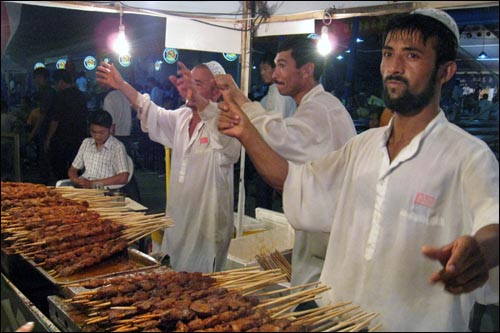 칭다오 맥주축제 현장에서 중국 소수민족 상인들이 춤을 추며 꼬치 안주를 판매하고 있다.