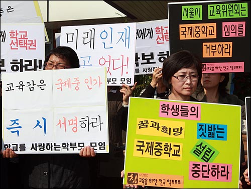  14일 오후 서울 사직동 유아교육진흥원 앞에서 특성화중학교 의견정취를 위한 공청회 시작전 국제중 설립에 찬성하는 학교를 사랑하는 학부모 모임(왼쪽)과 국제중 설립을 반대하는 참교육을 위한 전국학부모회가 나란히 손피켓을 들어보이고 있다.