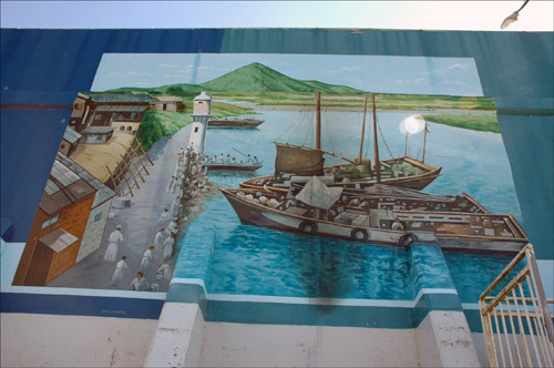 영산포등대 주변 벽체에 그려져 있는 옛 시절의 상인들과 배가 정박해 있는 그림