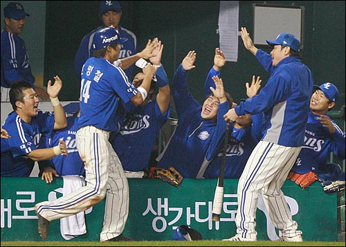  삼성 신명철이 17일 저녁 서울 잠실야구장에서 열린 2008 프로야구 플레이오프 2차전 두산과의 경기에서 연장 14회초 2사 3루 박한이의 좌전안타때 홈인하여 더그아웃에서 팀동료들의 축하를 받고 있다.