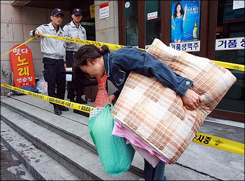 21일 오전 서울 강남구 논현동 D고시원 사건현장에서 고시원에 거주하고 있던 재중동포 여성이 이불과 짐을 챙겨들고 나오고 있다. 