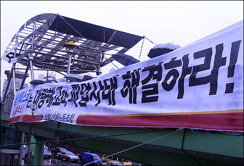 이랜드 노동조합원들이 10월 22일 오후 신도림역 광장 육교에 이랜드 파업사태 해결을 촉구하는 플래카드를 걸고 있는 모습. 