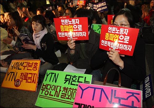 시민들이 24일 저녁 YTN 구본홍 사장 출근저지 투쟁 100일을 기념하며 서울 남대문로 YTN사옥 앞에서 연 촛불문화제에 참가해 정부의 언론자유 탄압을 규탄하며 손피켓을 들어보이고 있다.