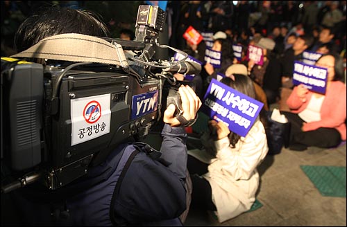  YTN 카메라 기자가 24일 저녁 서울 남대문로 YTN사옥 앞에서 열린 YTN 구본홍 사장 출근저지 투쟁하는 100일 기념 촛불문화제에서 카메라에 '공정방송' 스티카를 붙이고 취재를 하고 있다.