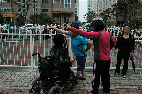 지난 10일 휠체어를 탄 1단지 주민이 "왜 사람이 다니는 길을 담장을 쳐서 막냐"고 항의하자 2단지 주민들이 이를 에워싸고 "돌아서 다니라"고 소리를 지르고 있다.