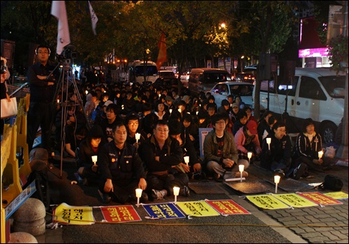 300여개의 촛불을 밝힌 각 연대단체와 시민들. 대오 앞에는 '해고자 전원복직', '비정규직 철폐하라'등의 현수막이 놓여있다. 